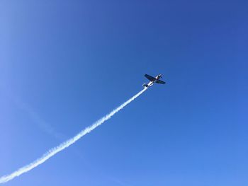 Low angle view of airplane flying in blue sky