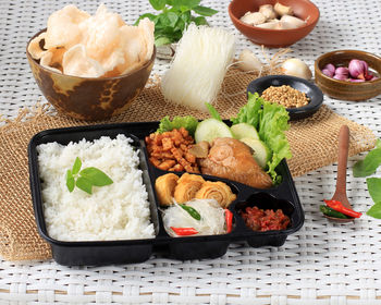 Rice box or nasi berkat, indonesian nasi kotak with soy sauce chicken, oreg tempeh, and spicy paste