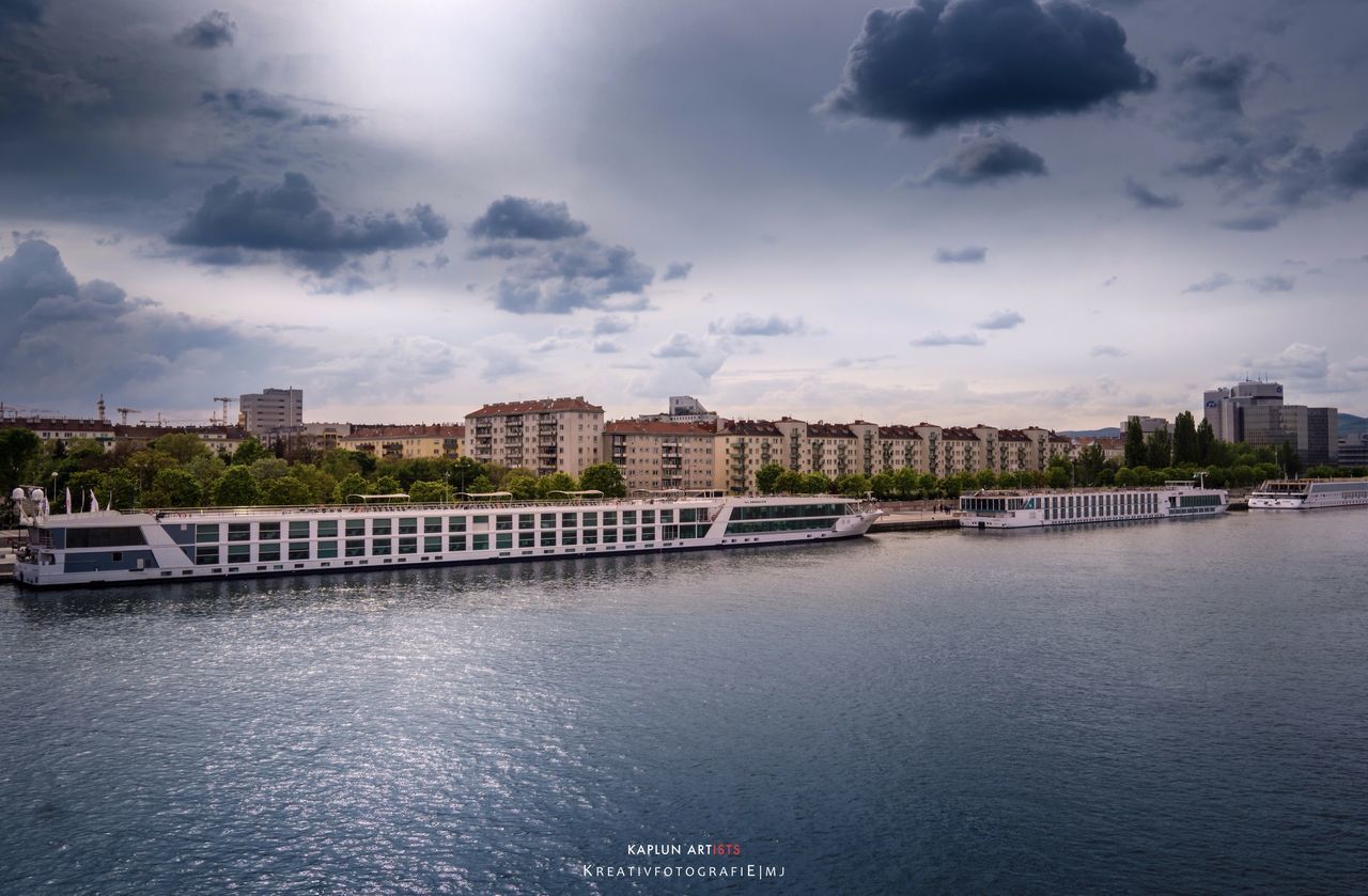 architecture, water, building exterior, built structure, sky, waterfront, cloud - sky, river, transportation, cloudy, city, nautical vessel, cloud, rippled, mode of transport, bridge - man made structure, residential building, canal, sea, cityscape