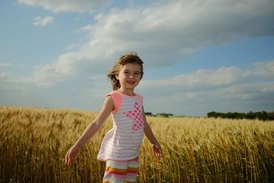 Cute girl standing on field against cereal plants