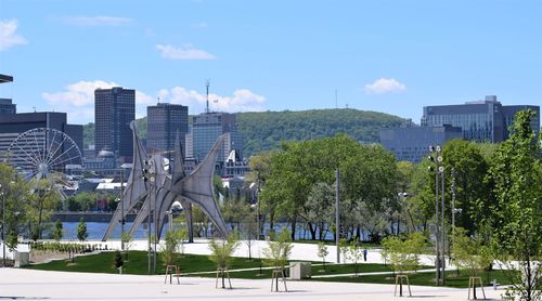 Trees and buildings in city against sky