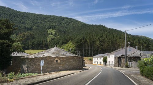 Road amidst trees and buildings against sky