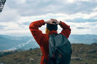 Rear view of man standing on mountain against sky