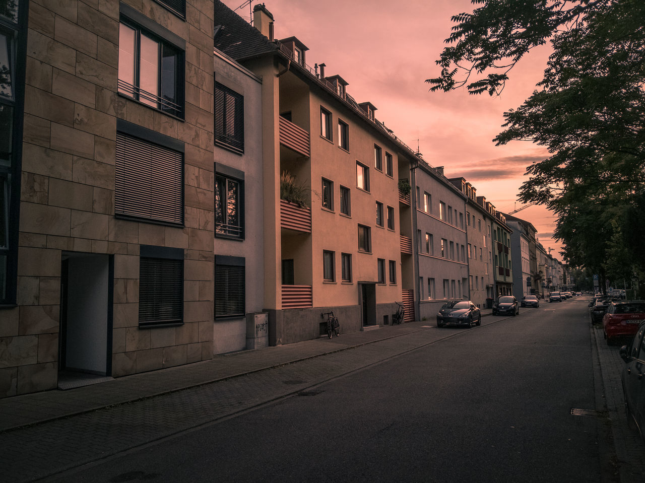 ROAD BY BUILDINGS AGAINST SKY AT SUNSET