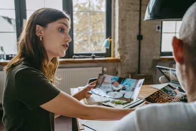 Side view of female food stylist talking to male colleague at studio