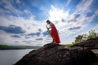 Woman standing on rock against sky