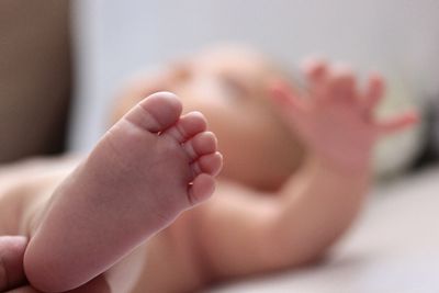 Low section of baby lying on bed