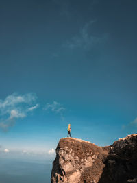 Man standing on rock against sky