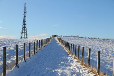 Wooden posts on snow covered field against sky