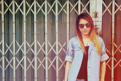 Portrait of young woman standing against shutter