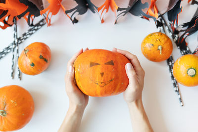 October 31st, halloween. the girl holds the carved face of a pumpkin in her hands.