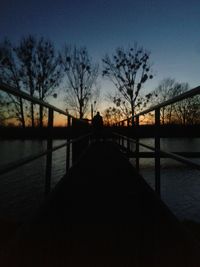 Silhouette bridge over river against sky during sunset