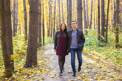 Full length portrait of young couple standing in forest