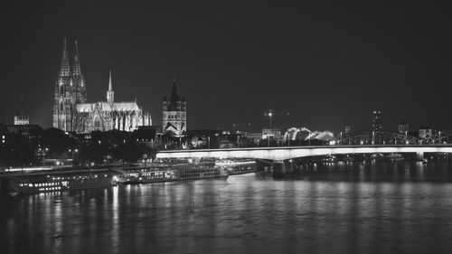 Illuminated bridge over river in city at night