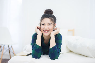 Portrait of smiling young woman lying on bed at home