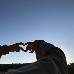 Low angle view of man hand against clear sky