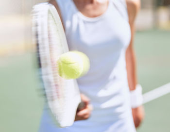 Portrait of young woman holding tennis