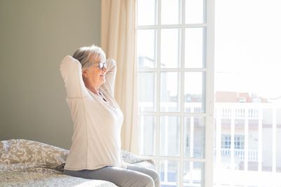 Side view of senior woman relaxing on bed at home