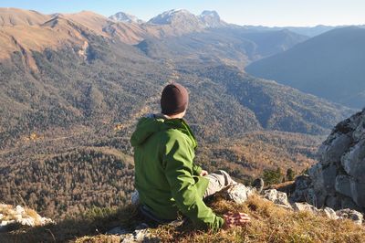 Rear view of man sitting on mountain