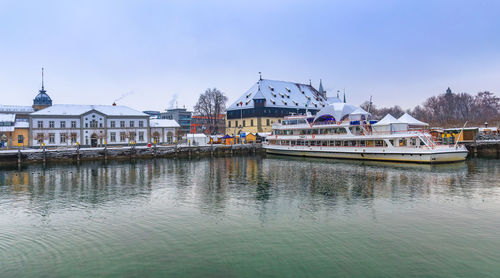 Buildings by river against sky