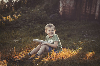 Smiling boy sitting on land
