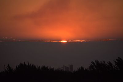 Scenic view of silhouette landscape against orange sky