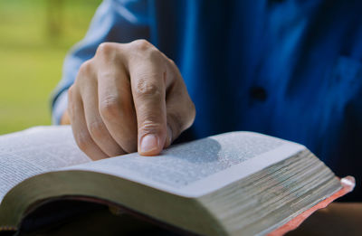 Close up hand of young prayer sitting outdoor for reading bible and worship god,