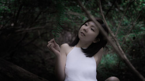 Portrait of woman standing by tree in forest