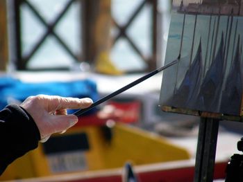 Cropped hand of painter painting on canvas outdoors