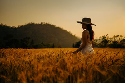 Rear view of woman standing on barley wheat field