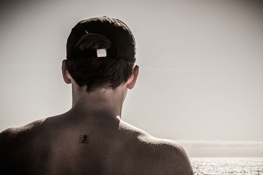 REAR VIEW OF SHIRTLESS MAN AGAINST SEA