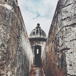 Narrow alley amidst stone wall against sky