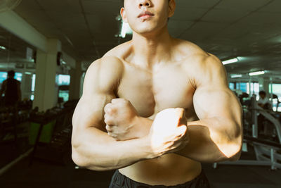 Shirtless muscular man flexing muscles at gym