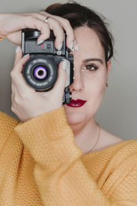 Portrait of woman photographing against gray background