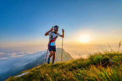 Man with poles in the mountains with sunset behind