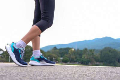 Low section of woman walking on road