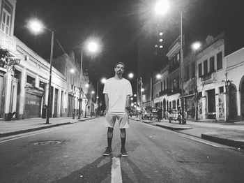 Full length of man with hands in pockets standing on road at night