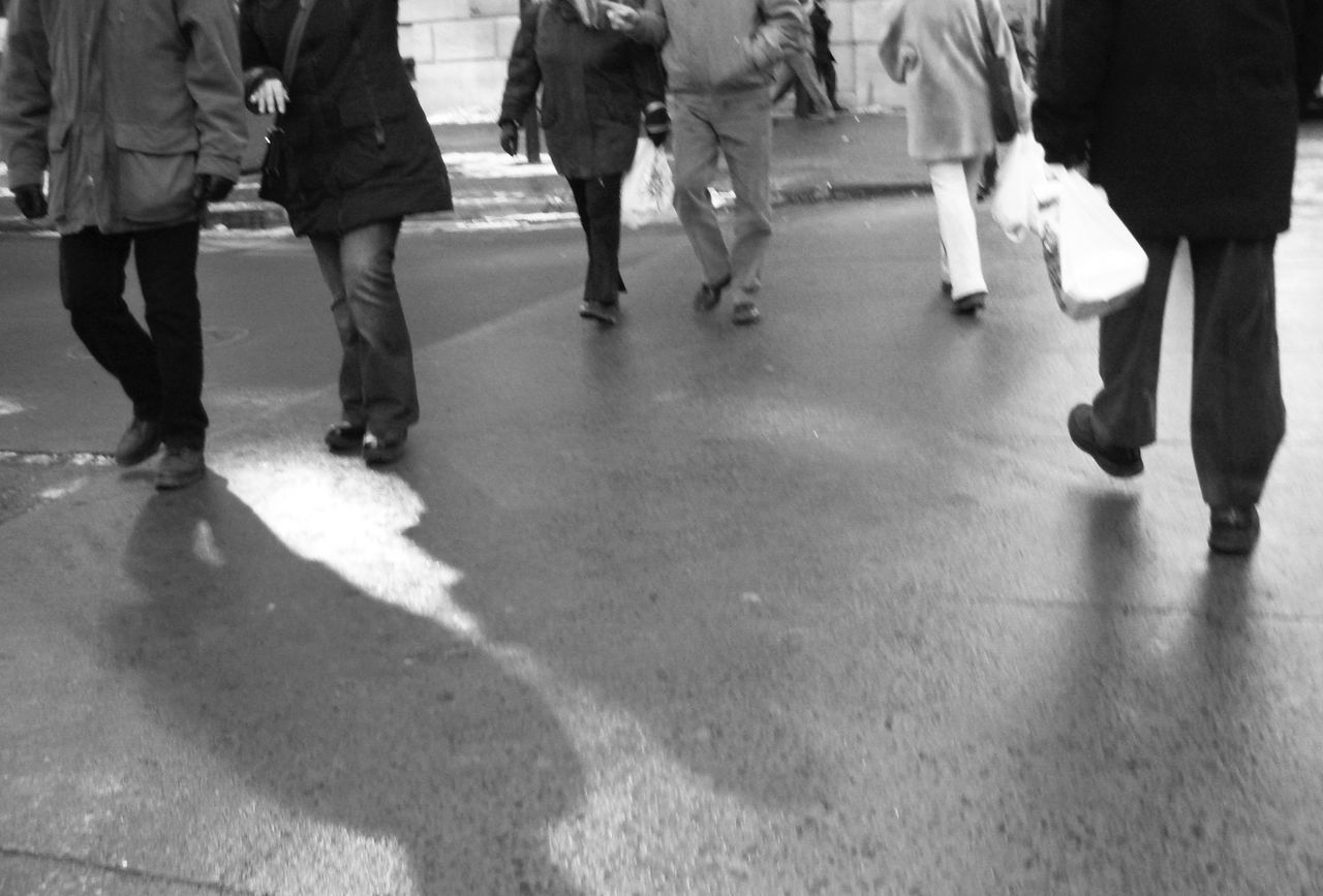 LOW SECTION OF PEOPLE WALKING ON ZEBRA CROSSING