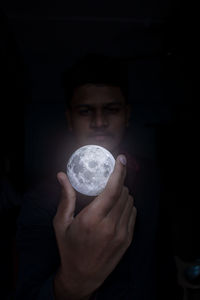 Portrait of man holding crystal ball in darkroom