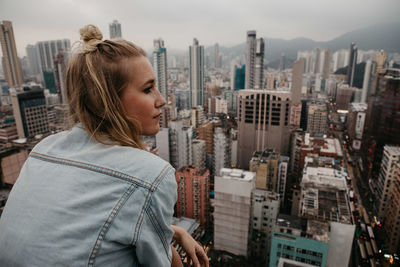Side view of young woman against cityscape