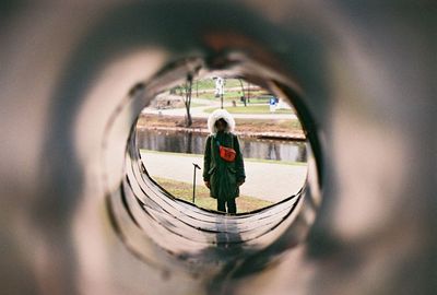 Woman in warm clothing seen through pipe