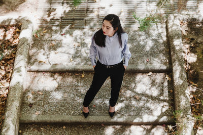 Portrait of young woman standing against tree