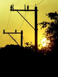 Silhouette electricity pylon against sky during sunset