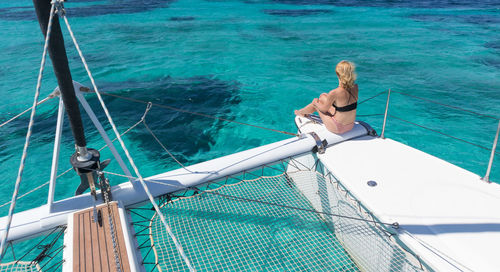 Rear view of woman sitting on boat in sea