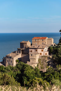 Buildings by sea against blue sky on the rocks