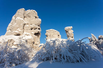 Low angle view of snowcapped mountain against clear blue sky