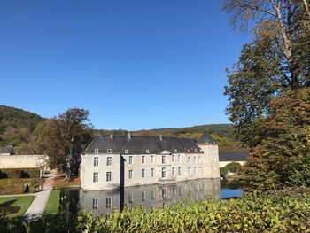 Houses and trees by plants against blue sky