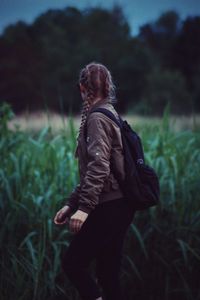 Side view of woman with backpack standing amidst plants at farm