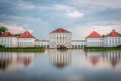 Reflection of building on lake against cloudy sky