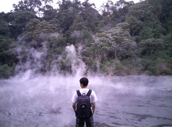 Rear view of man standing against waterfall